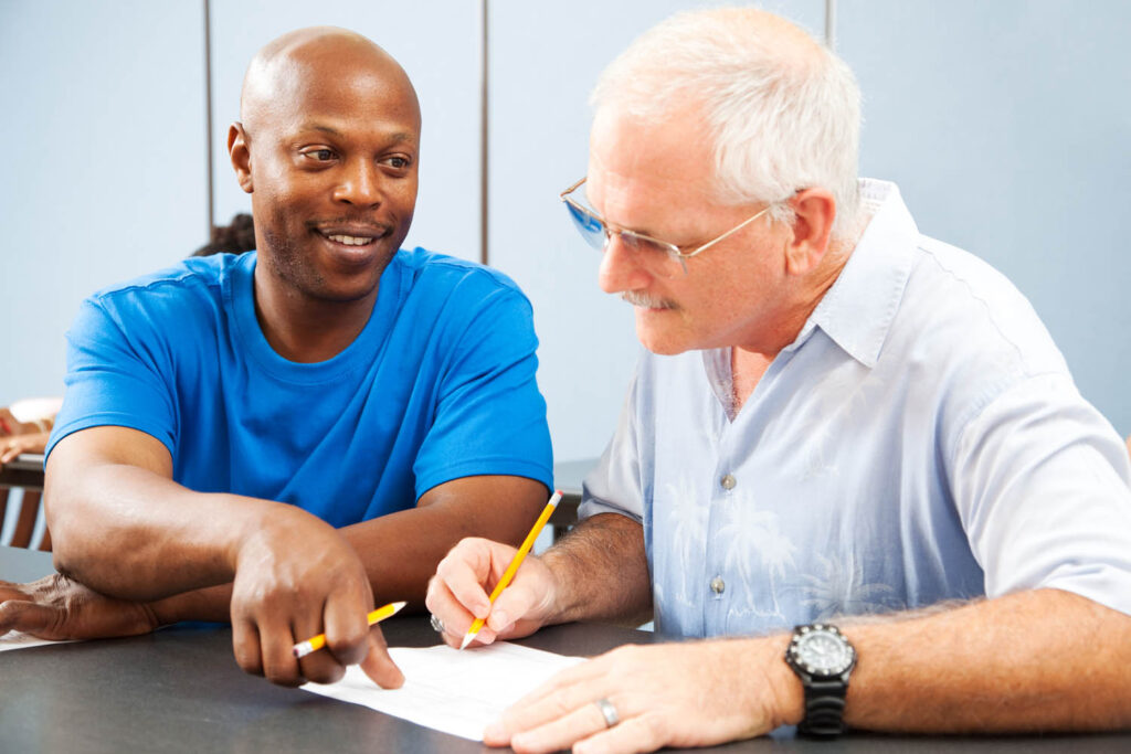 A young man helping a senior man complete some paperwork