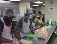Multiple volunteers preparing food in a commercial kitchen
