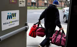 A volunteer carrying multiple insulated food bags