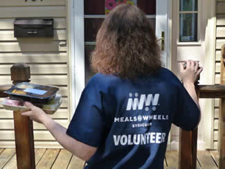 A Meals On Wheels volunteer delivers a meal to a homebound senior