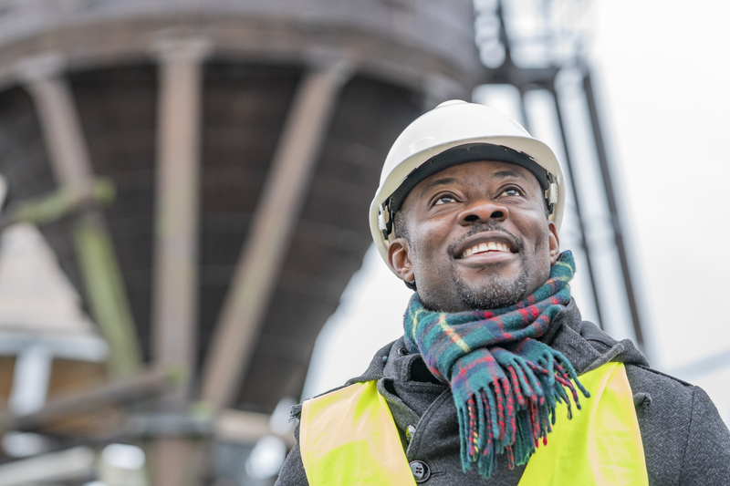 African-American man in a hard hat and safety vest at a work site.