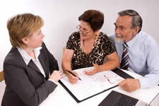 Three adults at a desk discussing a document in front of them.